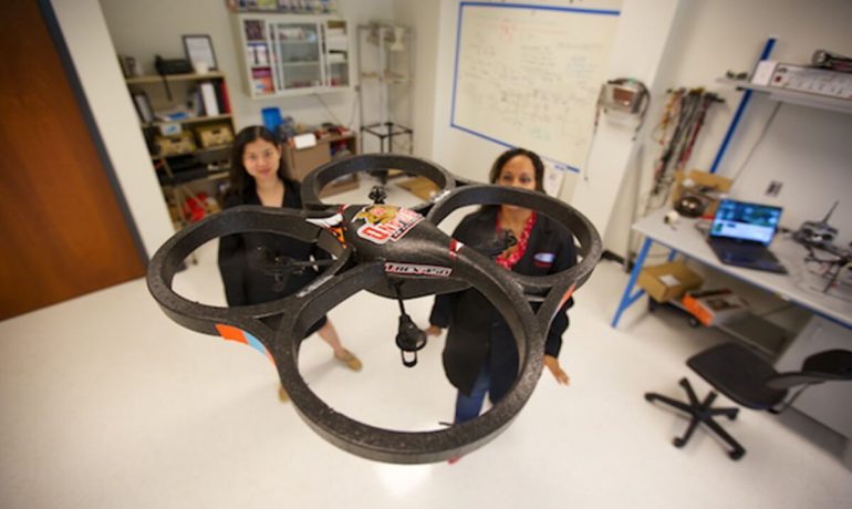 Female NIA researchers flying drone in lab