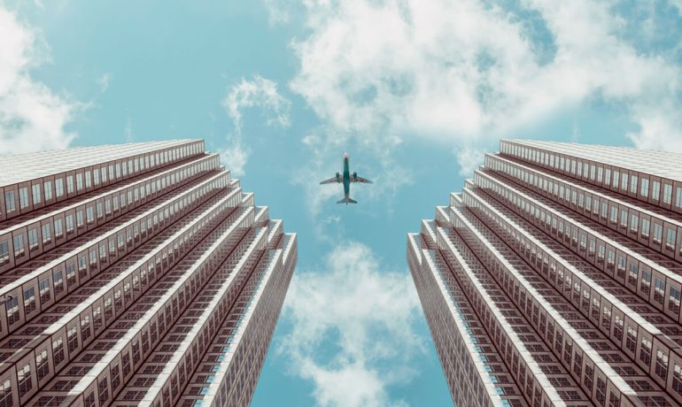 Airplane in the sky between two buildings from below