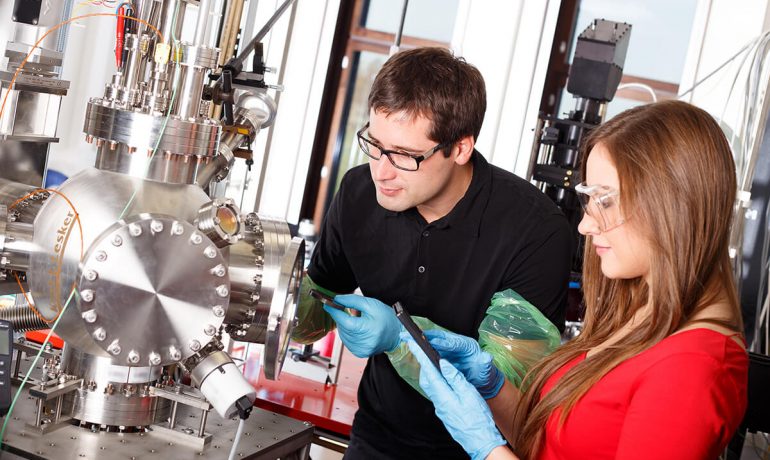 Research scientists working with laser deposits chamber technology